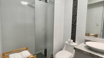 Un baño moderno con inodoro, lavabo y cabina de ducha de vidrio.