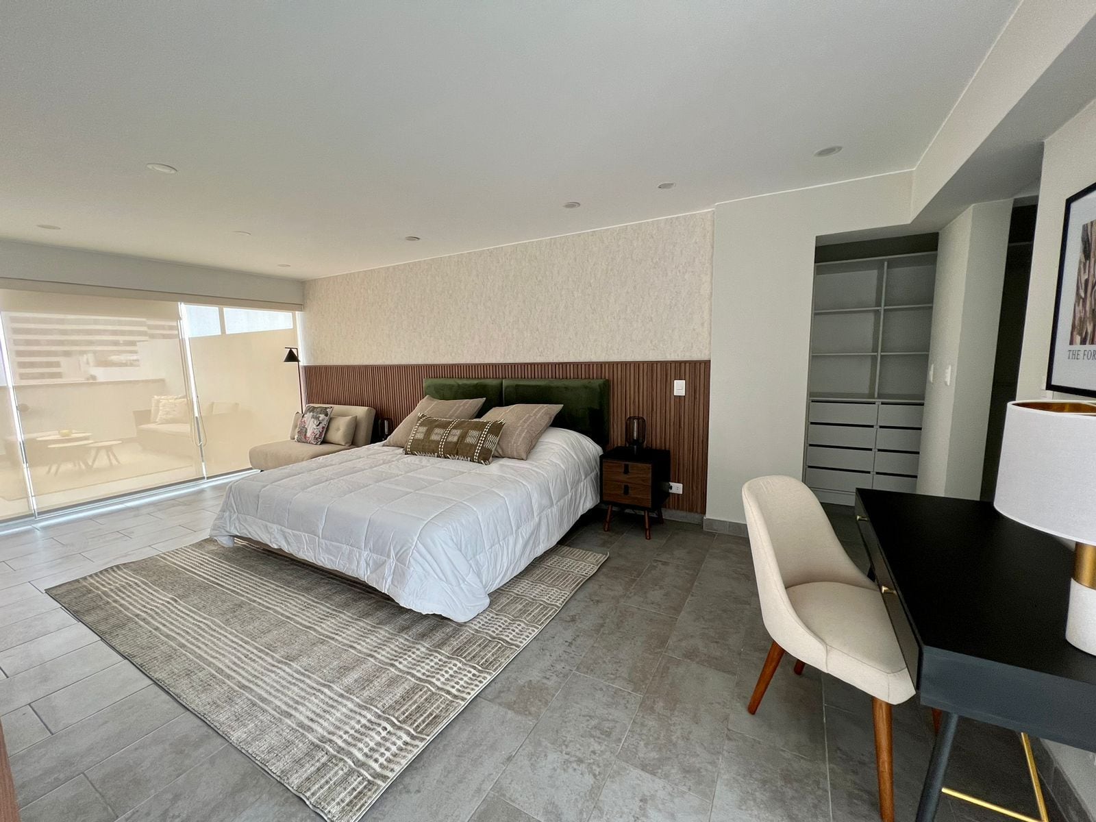 A modern bedroom with a large bed, a desk, and a chair.