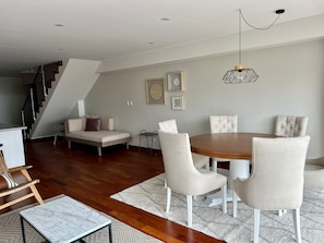 A modern living room with a dining area, wooden flooring, a staircase, and a chandelier. - Walk to Larcomar | Peaceful 7th Floor Flat • AC (Miraflores)