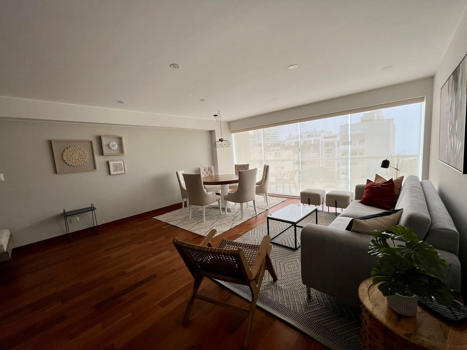 Una sala moderna con comedor, ventanas amplias y vista a la ciudad.