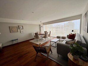 Una sala moderna con comedor, ventanas amplias y vista a la ciudad.