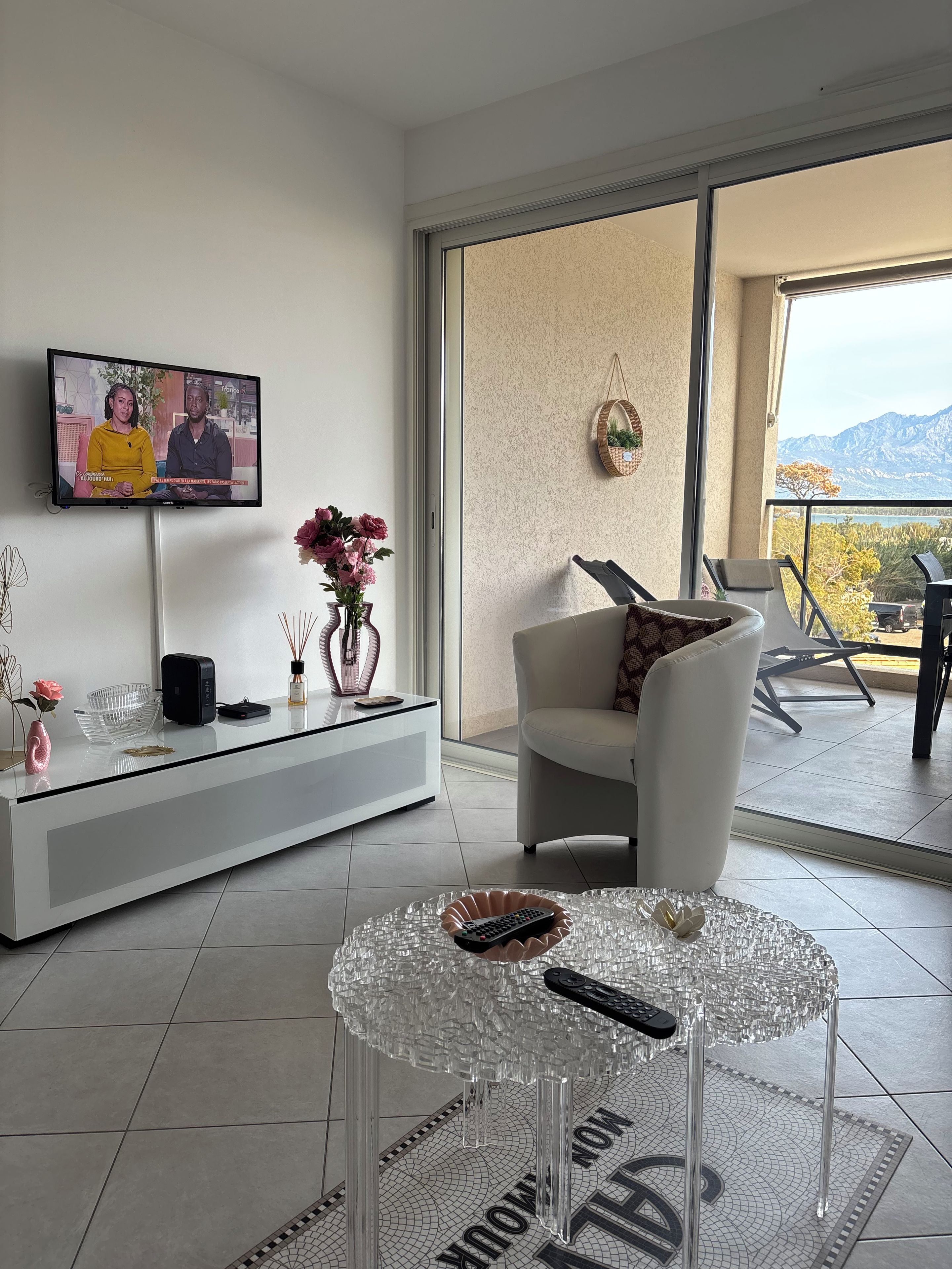 A modern living room with a flat-screen TV, a glass coffee table, and a sofa.