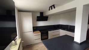 A compact kitchen with a black countertop, white cabinets, and a built-in oven. - New Listing (Malchow)