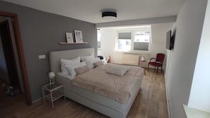 A bedroom with a bed, bedside table, and a chair. - New Listing (Malchow)