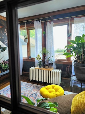 A room with a radiator, a yellow cushion, and various potted plants.