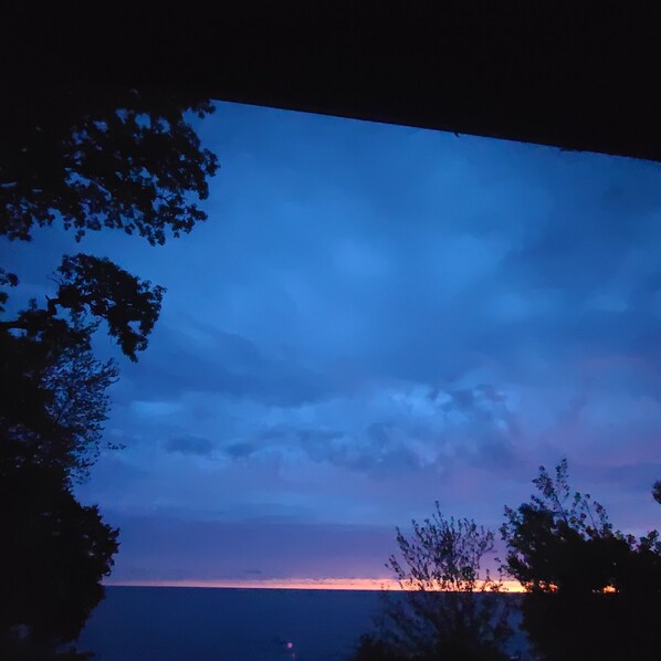 Vista sulla costa con cielo sereno e sagome di alberi.
