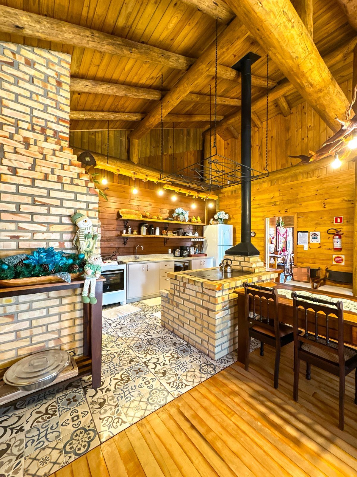 Une cuisine rustique avec des poutres en bois, une cheminée en briques et un luminaire suspendu.
