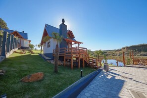 A lakeside property with a gazebo, a white building with a blue roof, and a clear view of the lake. - Hospedaria Morada das Grimpas (Lourenço)