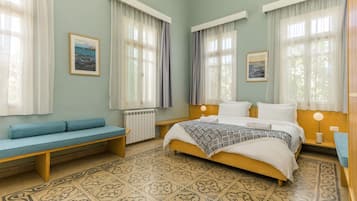 A bedroom with a bed, a bench, two bedside tables, and a radiator.