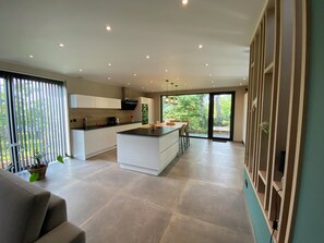 A modern kitchen with a central island, a dining area, and a large sliding glass door leading to a balcony. - New Listing (Hotton)