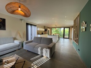 A modern living room with a sofa, a coffee table, and a hanging light fixture. - New Listing (Hotton)