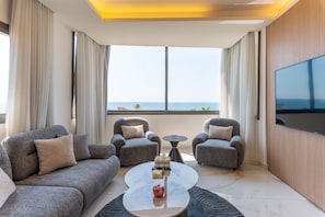 A modern living room with grey sofas, a coffee table, and a TV mounted on the wall.