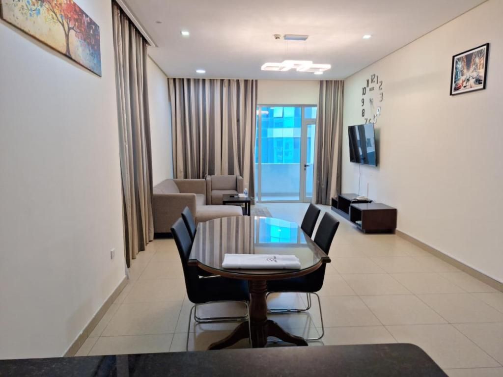 Uma sala de conferências moderna com uma mesa de vidro, cadeiras pretas, um sofá e uma TV na parede.