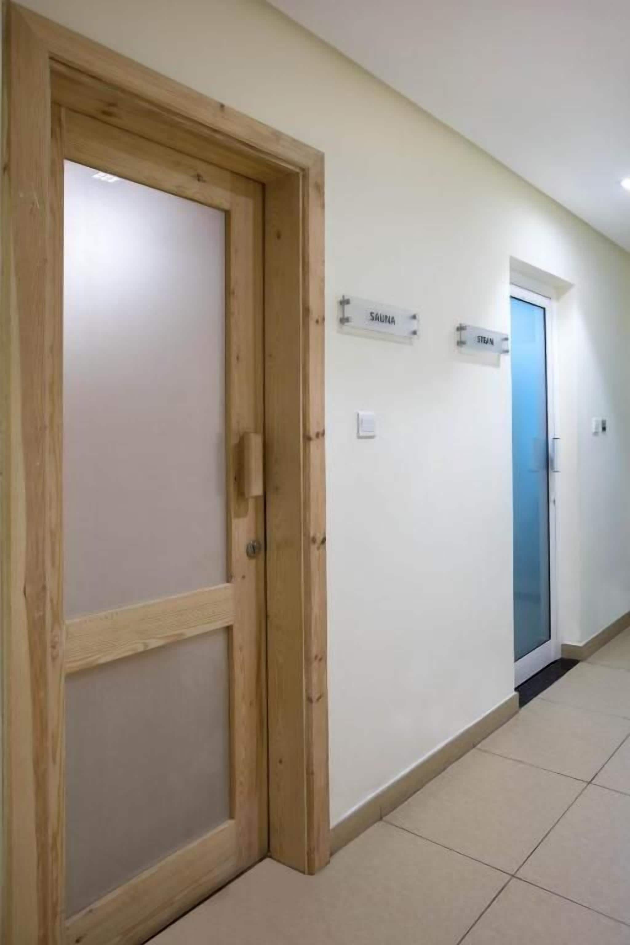 A hallway with a wooden door, a sign indicating a sauna, and a blue door.