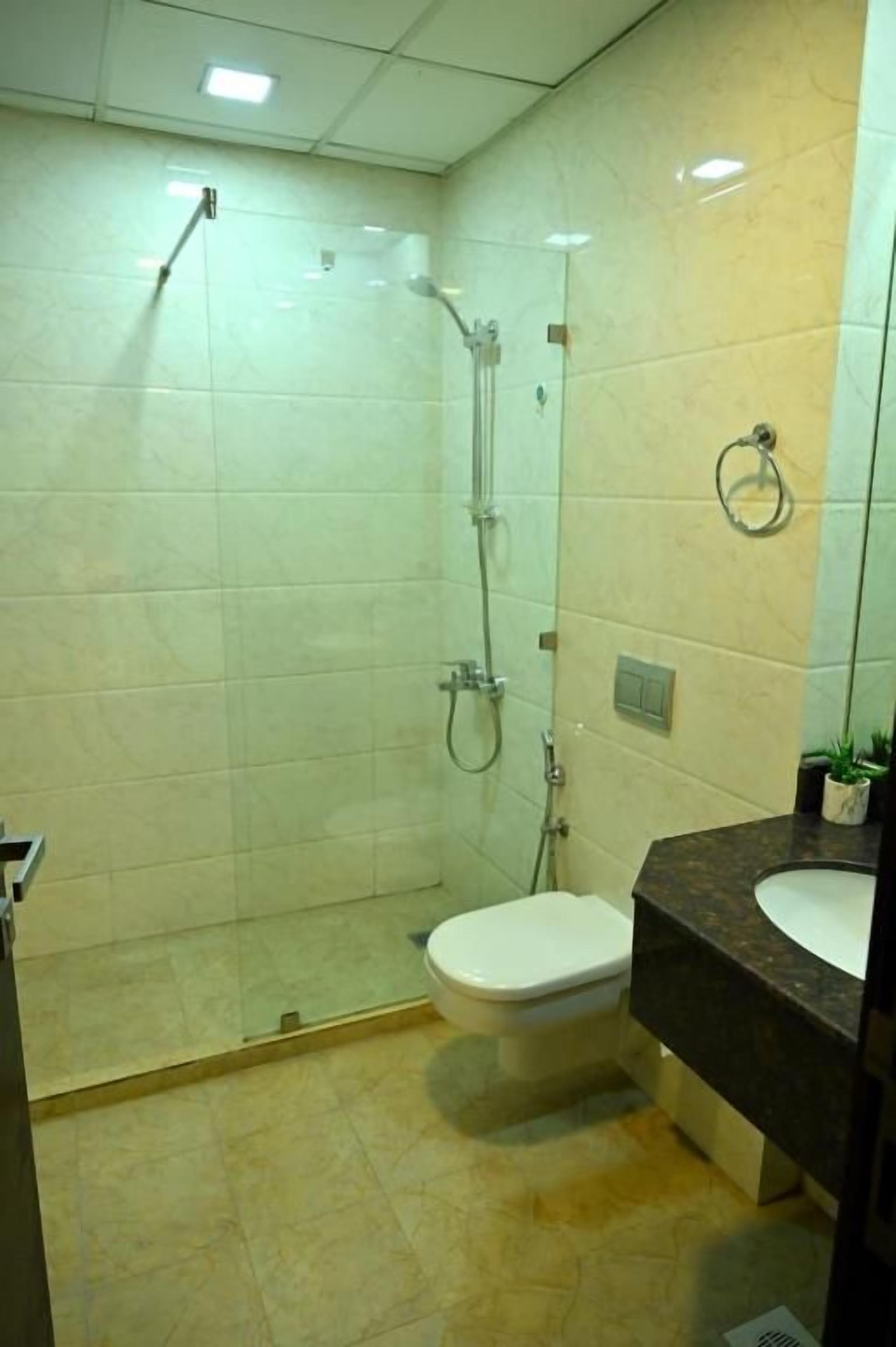Un baño con cabina de ducha de vidrio, inodoro y lavabo con espejo.
