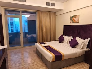 A hotel room with a bed, a sliding door to a balcony, and a painting on the wall. - Aspire Tower (Manama)