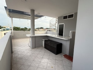 A balcony with a tiled floor, a white column, a black cabinet, and a white railing. - Cozy 1-bedroom apartment in delightful Machala with AC (Machala)