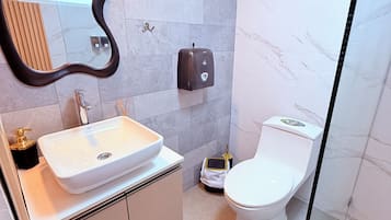 A modern bathroom with a white sink, a toilet, and a hand dryer.