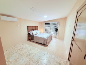 Une chambre à coucher comprenant un lit, une armoire et une fenêtre munie d’une moustiquaire de sécurité.