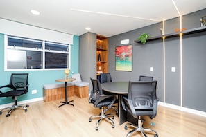 A modern conference room with a round table, black office chairs, a small side table with a globe, and a window with blinds. - New Listing (São Paulo)
