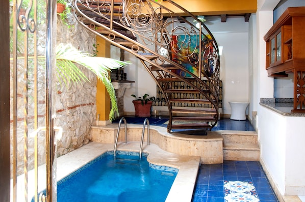 Piscina com escadaria espiral de metal que dá acesso a um nível superior.