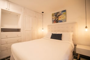 Ein Schlafzimmer mit einem Bett, einem Schminktisch, einem Nachttisch und einem Bild an der Wand.