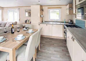 A compact kitchen with a dining area, a built-in oven, and a microwave. - Sublime 2 Caravan (Pet) (St. Leonards, Ringwood)