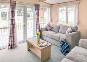 A living room with a grey sofa, a wooden coffee table, and a striped bag. - Sublime 2 Caravan (Pet) (St. Leonards, Ringwood)