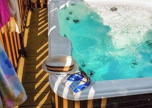 A wooden deck with a hot tub, a hat, and sunglasses on the edge. - Sublime 2 Caravan (Pet) (St. Leonards, Ringwood)
