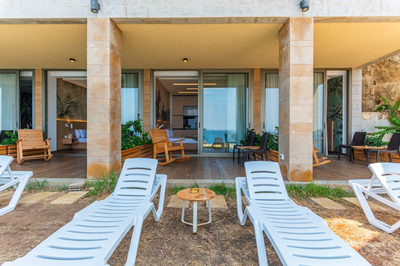 A covered outdoor area with lounge chairs, a small table, and a seating area with chairs and a sofa.
