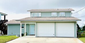 Ein zweigeschossiges Haus mit Garage, überdachter Veranda und kleinem Vorgarten.