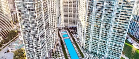 A high-rise building with a central courtyard featuring a swimming pool, surrounded by other high-rise buildings.
