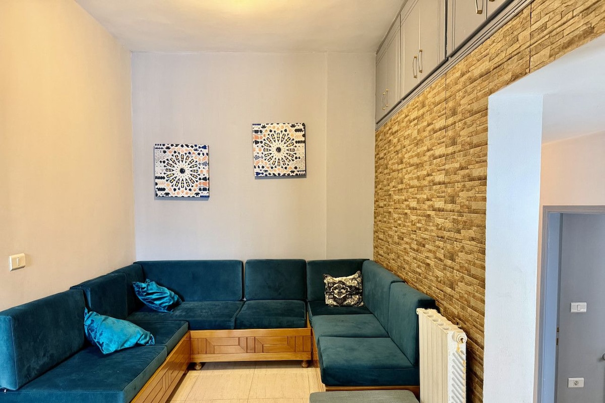 Ein Eckwohnzimmer mit einem Ecksofa, zwei Wandpaneelen zur Dekoration, einer Ziegelwand als Blickfang und einer Heizung.