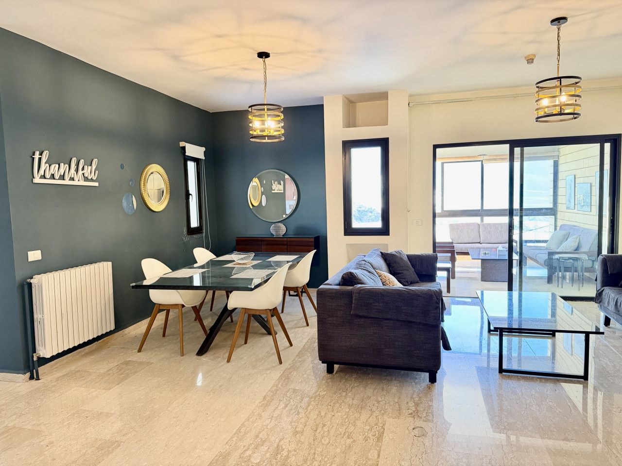 A modern living room with a dining area, a sofa, and a glass table.