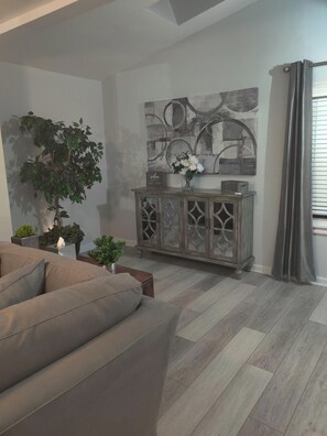 Een woonkamer met een bank, een kast met decoratieve objecten en een groot abstract schilderij aan de muur.