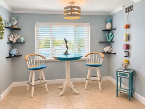 A dining area with two chairs, a table, and decorative items on shelves. - Cozy 1BR Beach Retreat. Just Blocks from Clearwater Beach (Clearwater)