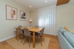 Een eetruimte met een houten tafel, zes stoelen, een vloerlamp en twee ingelijste kunstwerken aan de muur.