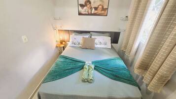 A neatly made bed with a patterned bedspread, a decorative pillow, and a wall-mounted picture.