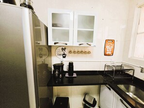 A compact kitchen with white cabinets, a black countertop, and a coffee maker.