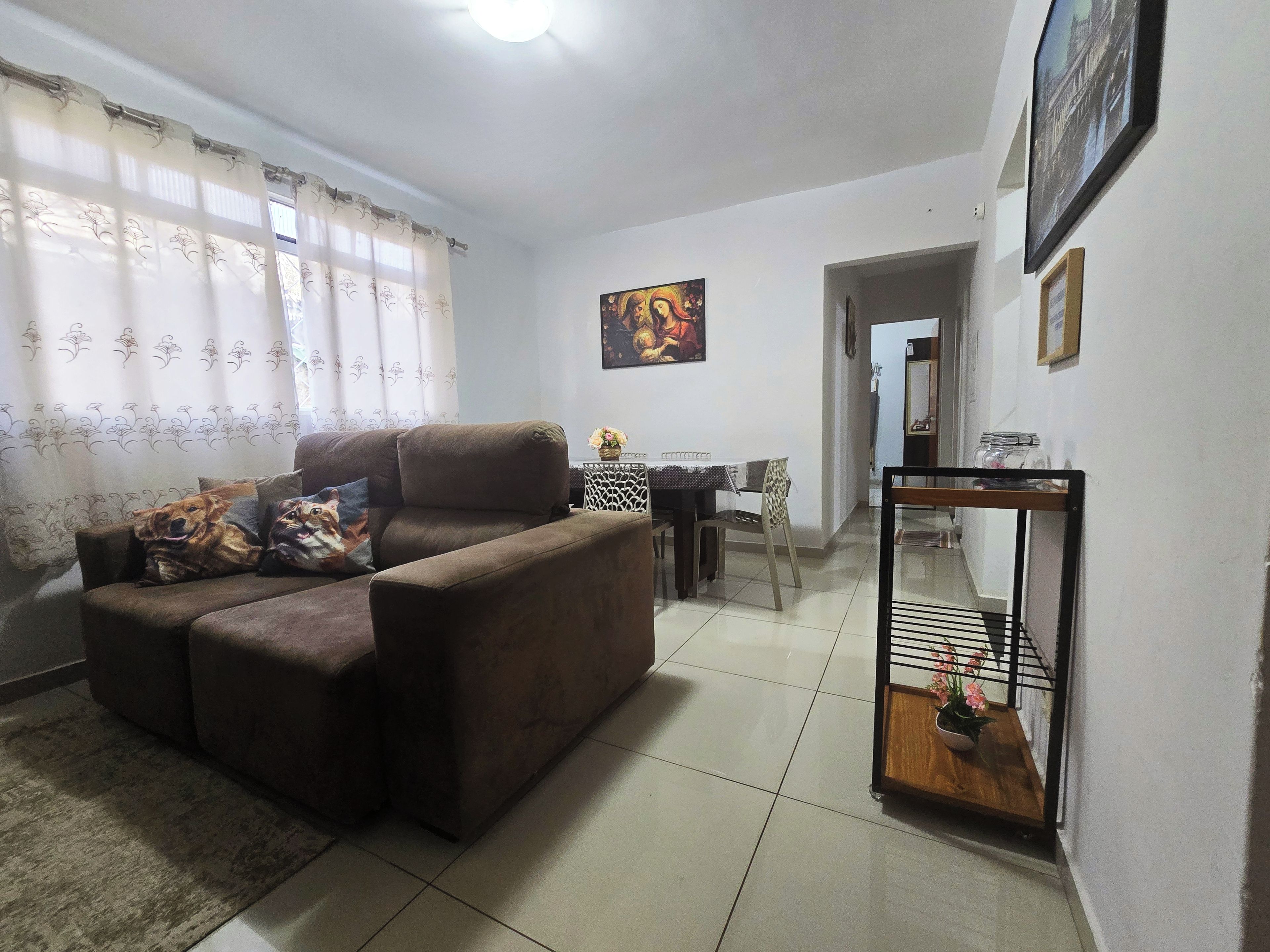 A living room with a sofa, a dining table, and a painting on the wall.