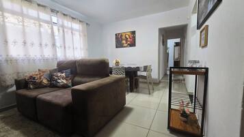 A living room with a sofa, a dining table, and a painting on the wall.