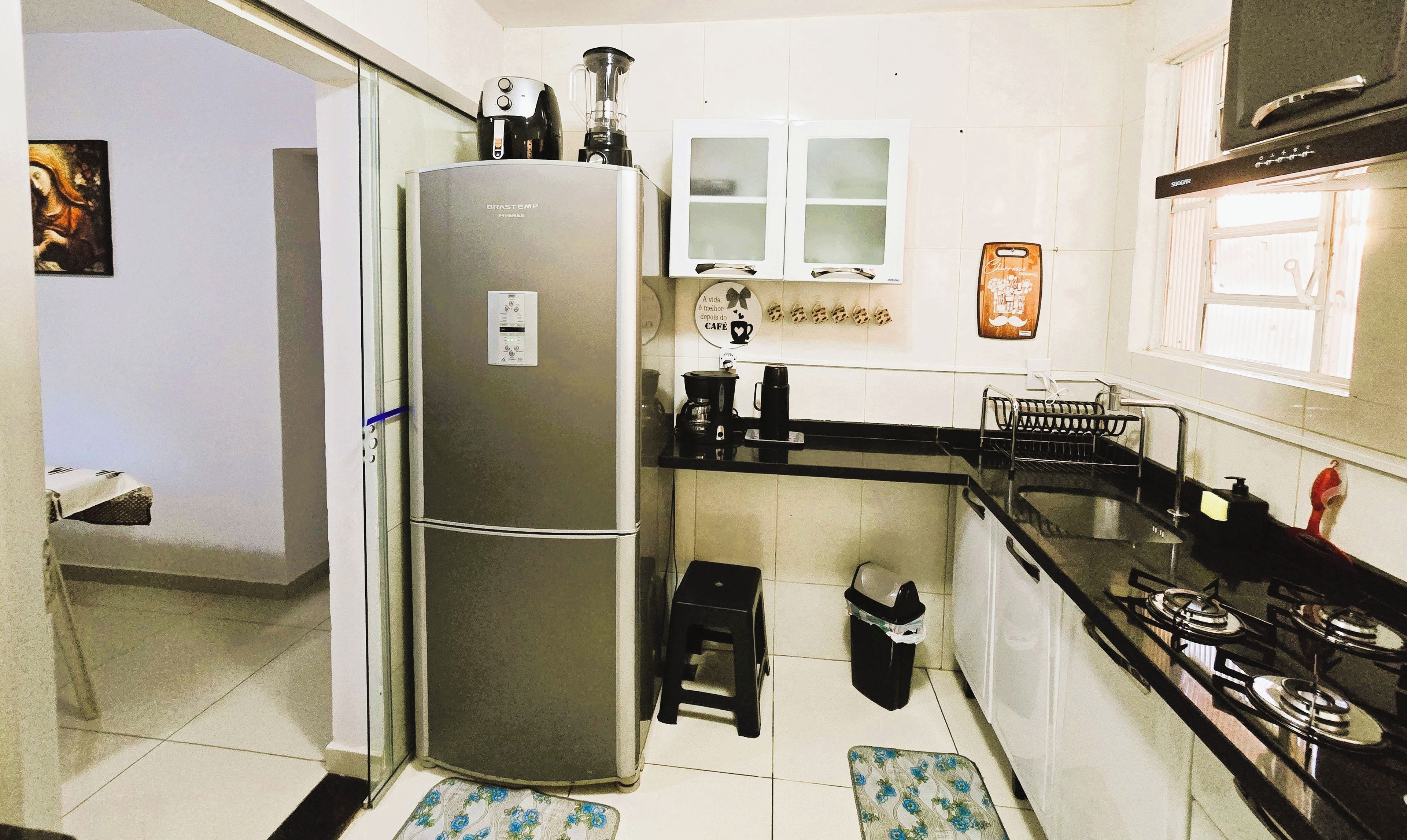 A compact kitchen with a refrigerator, a coffee maker, and a stove.