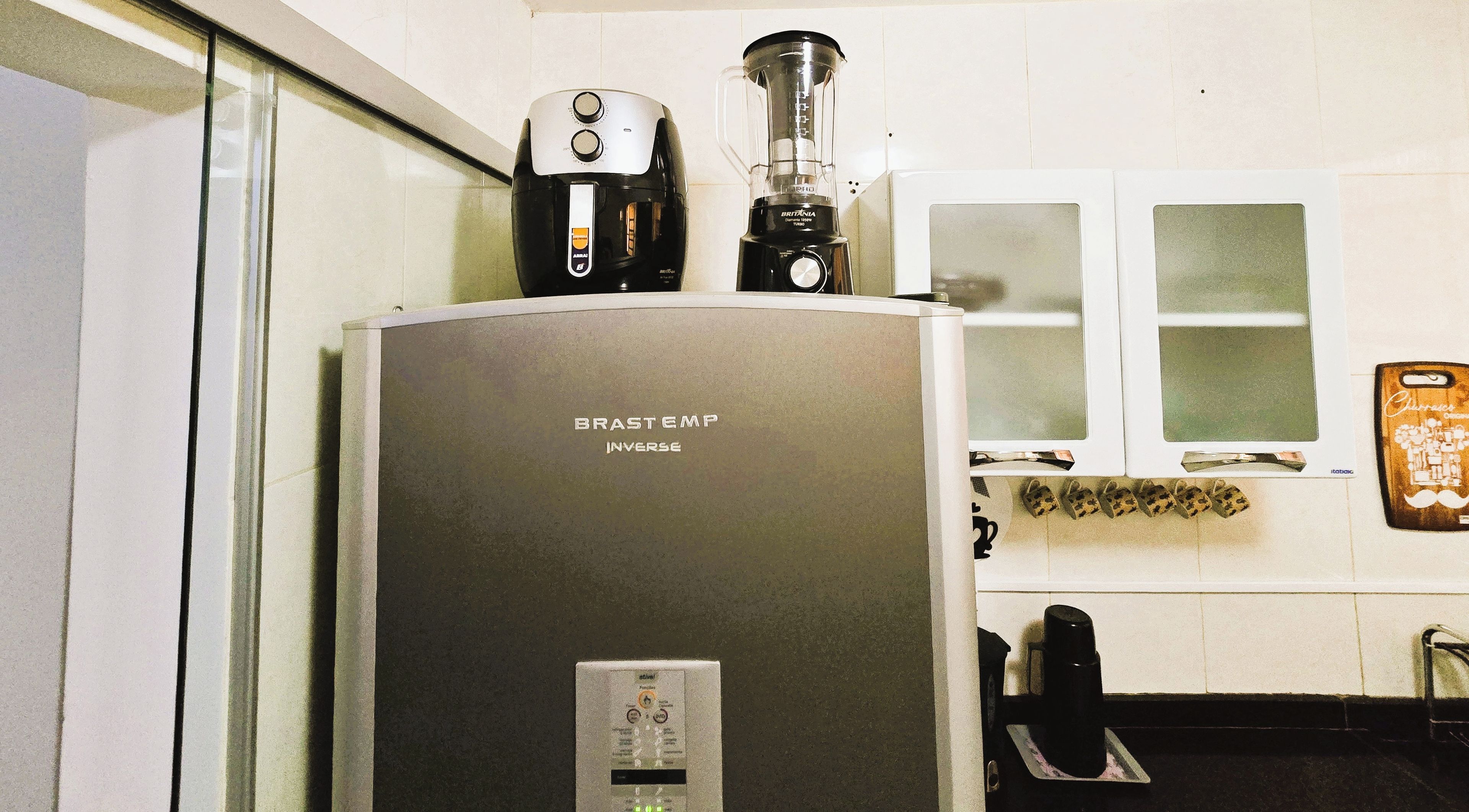 Una cocina con un refrigerador, una cafetera y una licuadora.