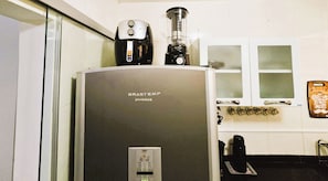 A kitchen with a refrigerator, a coffee maker, and a blender on top.