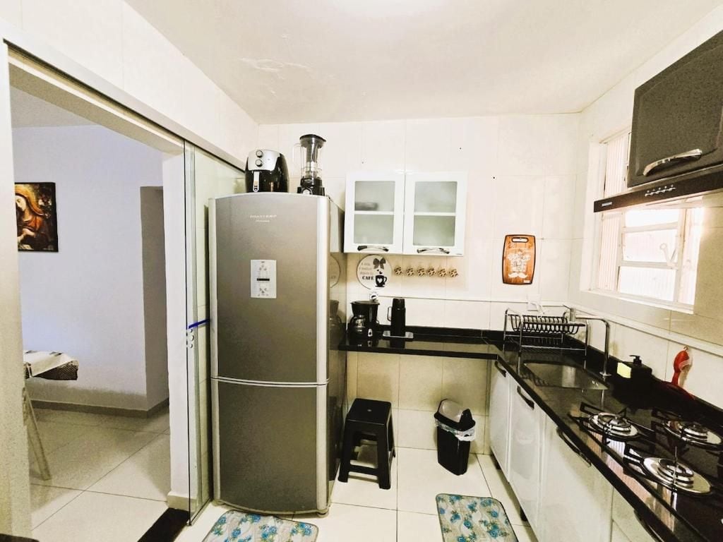 Cocina compacta con refrigerador, estufa y armarios.