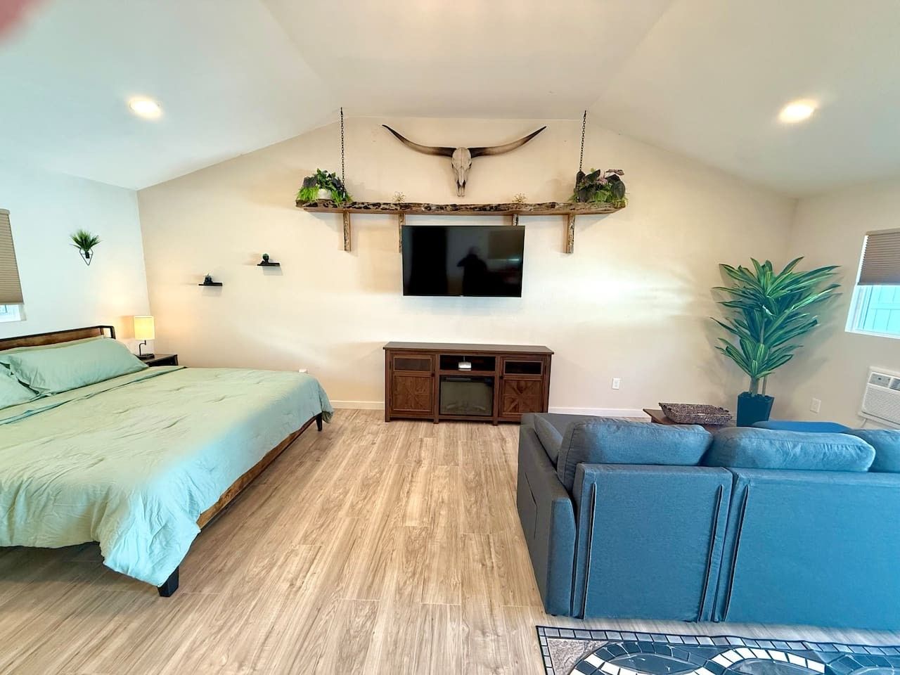 Une chambre à coucher comprenant un lit, un canapé, une télévision, une armoire en bois et un élément décoratif fixé au plafond.