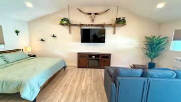 Une chambre à coucher comprenant un lit, un canapé, une télévision, une armoire en bois et un élément décoratif fixé au plafond.
