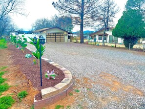 A residential property with a gravel driveway, a garage, and a landscaped garden area with young plants.