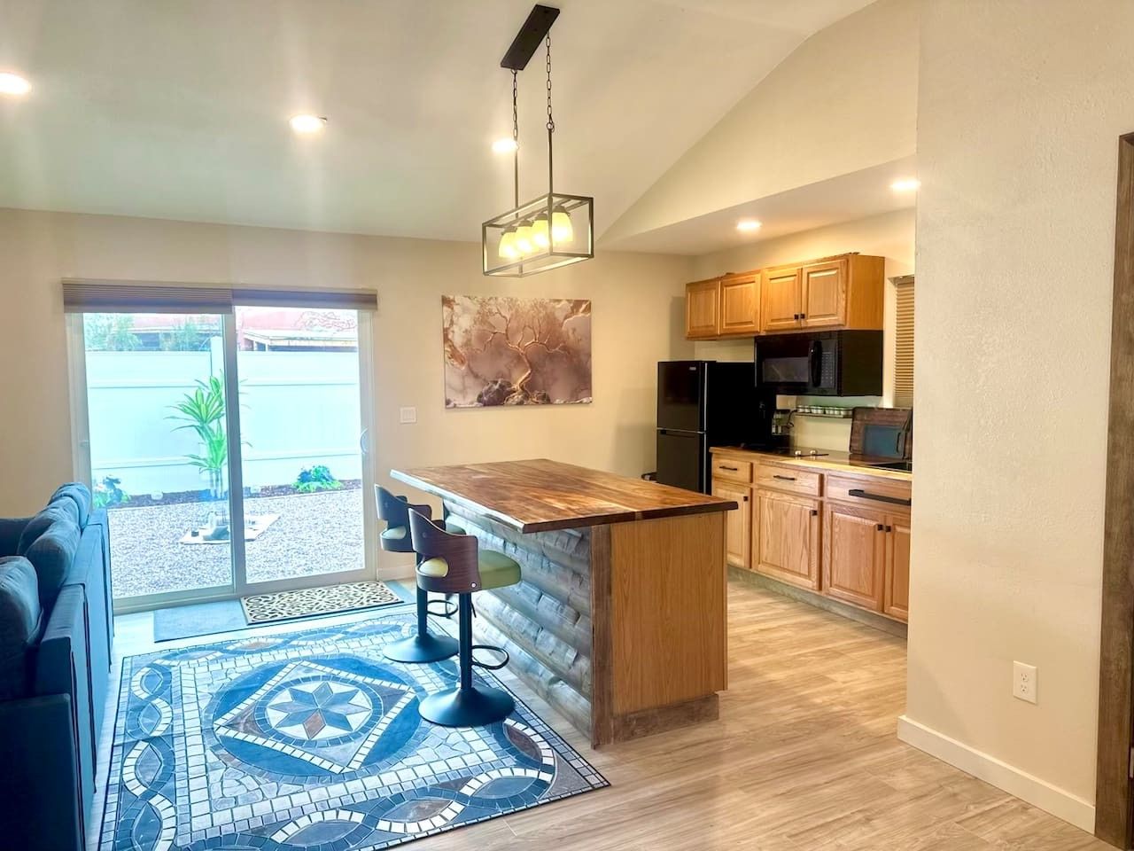 A modern kitchen with wooden cabinets, a built-in island, and a dining area with a bar stool.