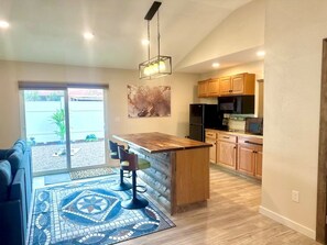 A modern kitchen with wooden cabinets, a built-in island, and a dining area with a bar stool.